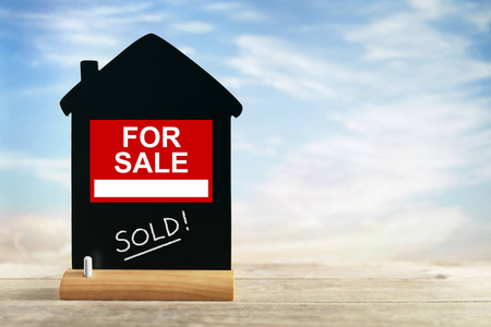 木质背景上的银色钥匙与房屋顶部视图符号 房地产广告的视觉语言